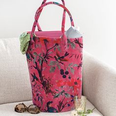 a pink tote bag sitting on top of a white couch next to a glass