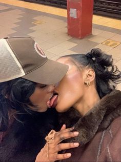 two women are kissing each other on the subway platform