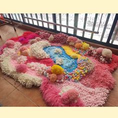 a large rug made out of various colored balls and pom poms on the floor