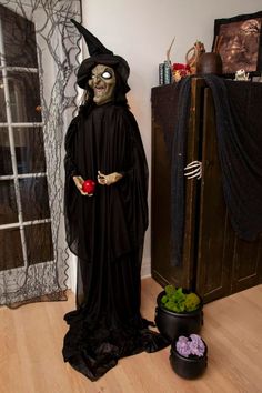 a skeleton dressed in black standing next to a potted plant