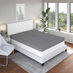 a white bed sitting in a bedroom on top of a hard wood floor next to a window