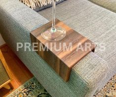 a table with a wine glass on top of it next to a couch in a living room