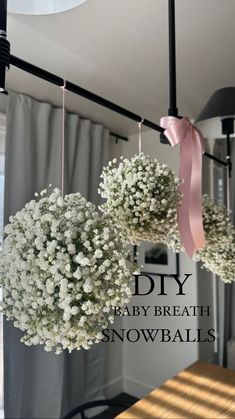 some white flowers hanging from the ceiling in front of a window with pink ribbon on it