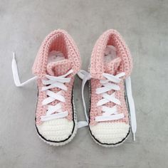 a pair of pink and white crocheted sneakers with laces on the top