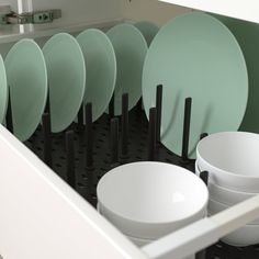 many plates and bowls are stacked in the dishwasher drawer, with black handles