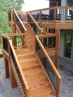 a wooden staircase with handrails and railing on the side of a house next to a patio