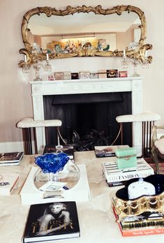 a living room filled with furniture and a fire place in front of a mirror on the wall