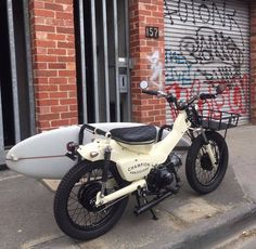 a white motorcycle parked next to a surfboard