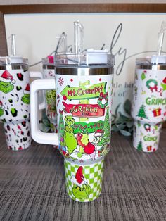 the grinch christmas travel mugs are lined up next to each other on a table