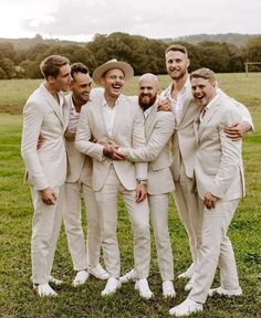 a group of men standing next to each other on top of a lush green field