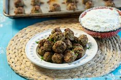 a white plate topped with meatballs next to a bowl of ranch dressing on a blue table