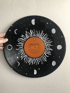 a hand is pointing at an orange and black record on a white wall with stars