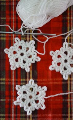 crocheted snowflakes are hanging on a line next to a ball of yarn