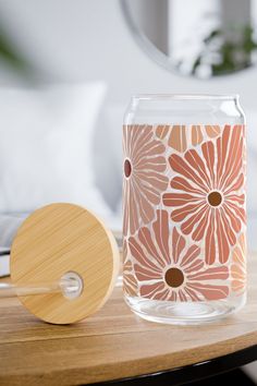 a glass vase sitting on top of a table next to a wooden coaster with a flower design