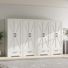 a large white cabinet with sliding doors in a living room next to a potted plant