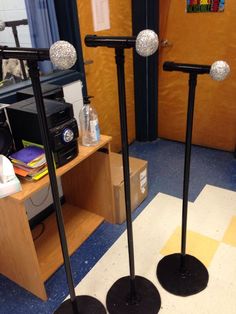 two black poles with silver balls on them in front of a desk and bookshelf