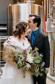 a bride and groom kissing in front of a brewery