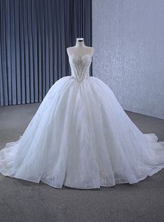 a white wedding dress on display in front of a curtain