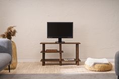 a flat screen tv sitting on top of a wooden stand next to a gray couch