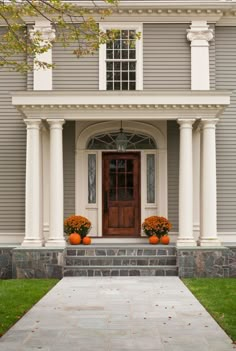 the front entrance to a house with two pumpkins on the steps