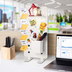 a laptop computer sitting on top of a desk next to a white board with sticky notes