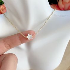 Tiny Mother of Pearl (Nacre) star necklace. The nacre has a high luster with white tones. Celestial jewelry is in at the moment. This is a lovely star necklace, it's a delight for the eyes! This dainty Mother of Pearl star, is made with a gold-plated chain. Perfect for everyday wear, this necklace looks great layered with other necklaces or by itself. When you put on a piece of jewelry, you probably focus on how it looks with your outfit or what it says about your style. Remember, in simplicity, Delicate Star-shaped Clavicle Necklace, Dainty White Choker With Delicate Chain, White Star-shaped Jewelry With Adjustable Chain, Tiny Star Shaped Minimalist Necklaces, Dainty Gold Chain Necklace With Star Charm, Dainty Star-shaped Gold Necklace, Tiny Star Minimalist Necklaces, Minimalist Tiny Star Necklaces, White Dainty Choker With Clavicle Chain