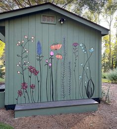 a green shed with flowers painted on the side