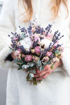 a woman in a white coat holding a bouquet of pink roses and lavenders on her wedding day