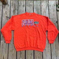 Show your love for the Florida Gators with this vintage Champion University of Florida Gators Orange Crewneck Sweatshirt. This sweatshirt is made from high-quality materials and features the Gators team logo prominently on the front. Perfect for football season and any Gators fan, this sweatshirt comes in size XL and is made by Tultex. perfect for both men and women. It is also perfect for regular season games and is a must-have for any sports fan. This item is made in Mexico and is perfect for Throwback Long Sleeve T-shirt For College, Oversized Vintage T-shirt, 90s Style Tops With Ribbed Cuffs For College, 90s Long Sleeve T-shirt For College, 90s Style Long Sleeve T-shirt For College, Oversized 90s Sweater For College, Oversized Long Sleeve Throwback Tops, 90s Crew Neck College Sweater, 90s Style Long Sleeve Sweatshirt Fan Merchandise