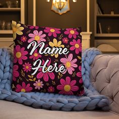 a pillow that says name here on it sitting on top of a couch next to a blue blanket