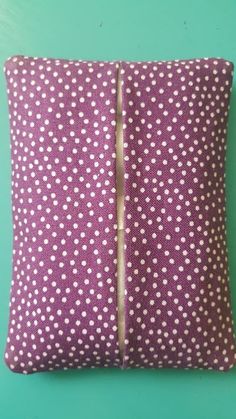 a purple and white polka dot pillow on a green background with zippered closures