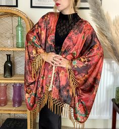 Dive into luxurious boho vibes with our new boho satin fringe kimono! Made using a soft well draping charmeuse satin, this oversized kimono will suit a variety of sizes. The pattern is a beautiful boho scene in red,rust, and gold colours with hand sewn gold fringe trim on the sleeves and bottom hem. Due to the loose fitting nature of this kimono it makes it a perfect piece for festivals, beach days and everyday wear. Length 26 inches ( not including fringing) Fringe trim 4 inches Depending on de Festival Kimono, Oversized Kimono, Tassel Jacket, Fringe Kimono, Kimono Duster, Gold Fringe, Satin Kimono, Boho Kimono, Fringe Trim