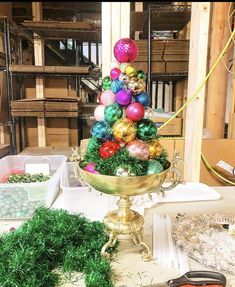 a christmas tree made out of ornaments in a gold bowl on a table with other items