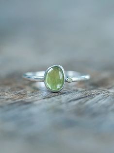 The rose cut peridot (August birthstone) shines alongside a tiny round green sapphire (September birthstone), both held securely in a bezel setting. Pair your peridot ring with peridot earrings to channel a free spirited and joyful vibe. Let this ring be the statement piece that adds a touch of whimsy and elegance to your style. Each piece of our jewelry is handcrafted with love. Lime Green Sterling Silver Birthstone Rings, Fine Jewelry Green Sapphire Ring With Rose Cut Diamonds, Green Sapphire Ring With Rose Cut Diamonds, Green Gemstone Sterling Silver Birthstone Ring, Sterling Silver Jewelry With Lime Green Accent Stones, Green Sapphire Sterling Silver Ring For May Birthstone, Green Sapphire Ring For May Birthstone In Sterling Silver, Green Gemstone Stackable Rings In Sterling Silver, Green Sapphire Ring Sterling Silver, May Birthstone