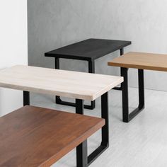 three wooden tables sitting next to each other on top of a white floor in front of a wall