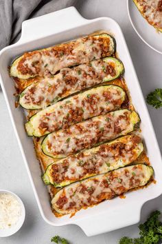 zucchini stuffed with meat and cheese in a white casserole dish