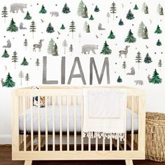 a baby crib in front of a wall with forest decals and the word llama on it