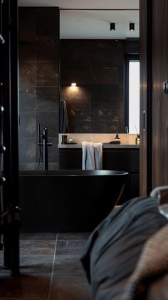 a large black bath tub sitting next to a bathroom sink in a room with dark walls