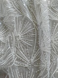 close up view of an embroidered fabric with white thread and sequins on it