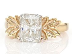 a gold ring with a white diamond surrounded by leaves