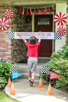 a young boy holding up a sign in front of a house with red, white and blue flags