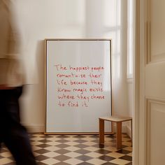 a person walking past a poster on the wall in a room with black and white checkered flooring