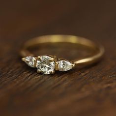 three pear shaped diamond engagement rings sitting on top of a wooden table