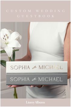 the wedding guest book is held by a woman in white dress and holding a flower