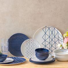 a table topped with plates and bowls filled with different types of blue dishes on top of a wooden table