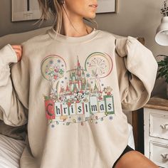 a woman sitting on top of a bed wearing a sweatshirt