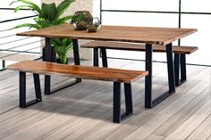 a wooden table with two benches next to a potted plant