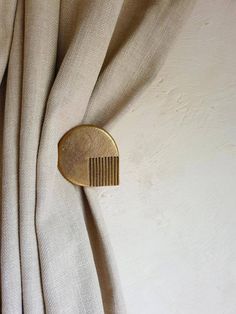 a gold hair comb on top of a beige curtain