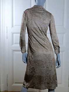 This German vintage beige and brown 1970s dress and closes in the front to below the waistline with six buttons. The retro dress has super-wide notch lapels and an abstract geometric pattern make up of diagonal lines of what look like upside-down Hershey Kisses. The long sleeves are cuffed and close with one button. The dress falls in a vertical narrow panel to the hips, and the lower part of the dress is attractively pleated. The dress is fully lined in a brown mesh nylon fabric. Brand label: I Brown Long Sleeve Vintage Dress For Spring, Beige Long Sleeve Vintage Dress For Formal Occasions, Beige V-neck Retro Dress, Retro Beige V-neck Dress, 1970s Fitted Beige Dress, Vintage Brown Knee-length Dress, Retro Long Sleeve Vintage Evening Dress, Retro Long Sleeve Evening Vintage Dress, Beige Long Sleeve Retro Vintage Dress