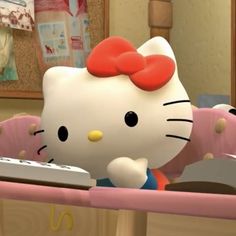 a hello kitty doll sitting in a baby crib with a remote on it's lap